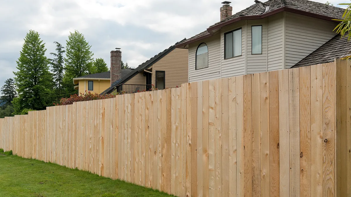 Fresh wooden fence boards installed along a residential property line